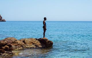 Black woman preparing to dive into blue sea