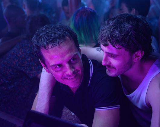 Two White men with arms around each other, purple hued lighting