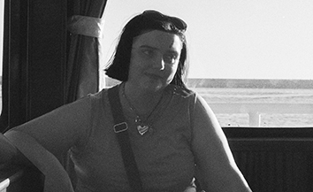 Black and white close-up photo of young White woman with short straight dark hair sitting on a ferry