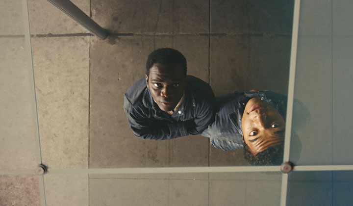 Two black boys in blue overalls looking up. Image take from above.