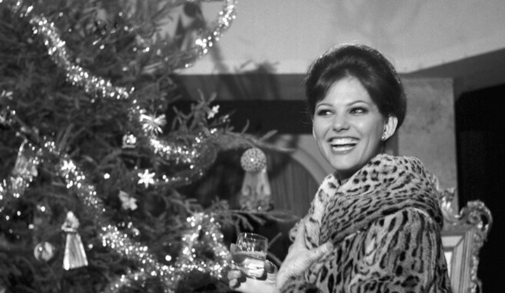 Young woman in fur coat smiling next to Christmas tree