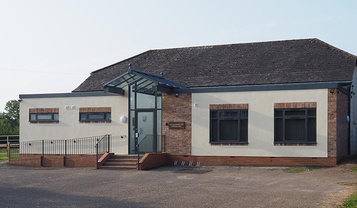 Low single storey village hall with cream-coloured rendering