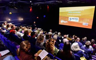 Auditorim with raked blue seating, orange slide reading Open Screen on screen. 