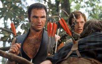 Man wearing black leather zipped jerkin carrying red arrows his back