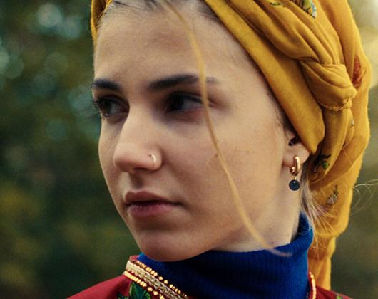 Young woman wearing yellow headscarf in close up looking to her right